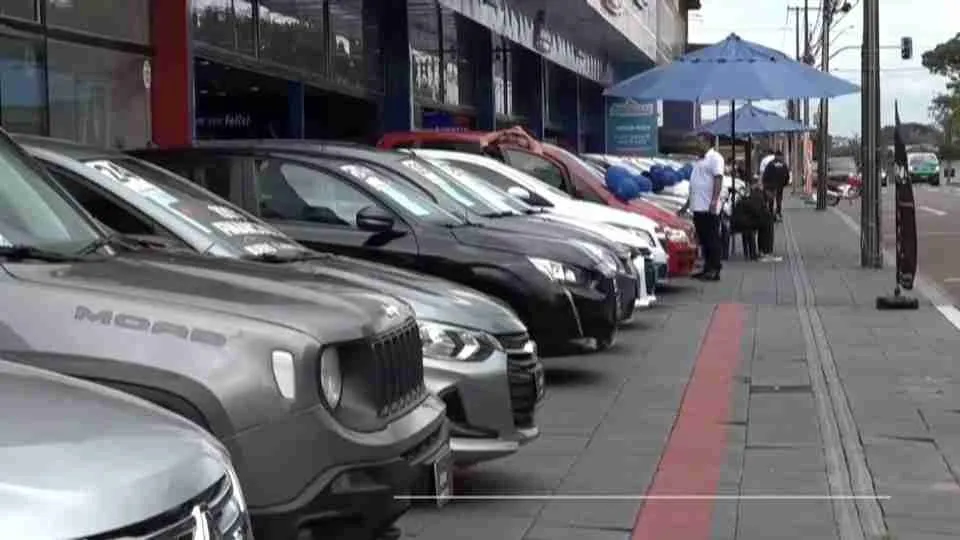 Carros expostos em frente a uma concessionária, ao lado da calçada, em Cascavel. Foto: Reprodução/CATVE